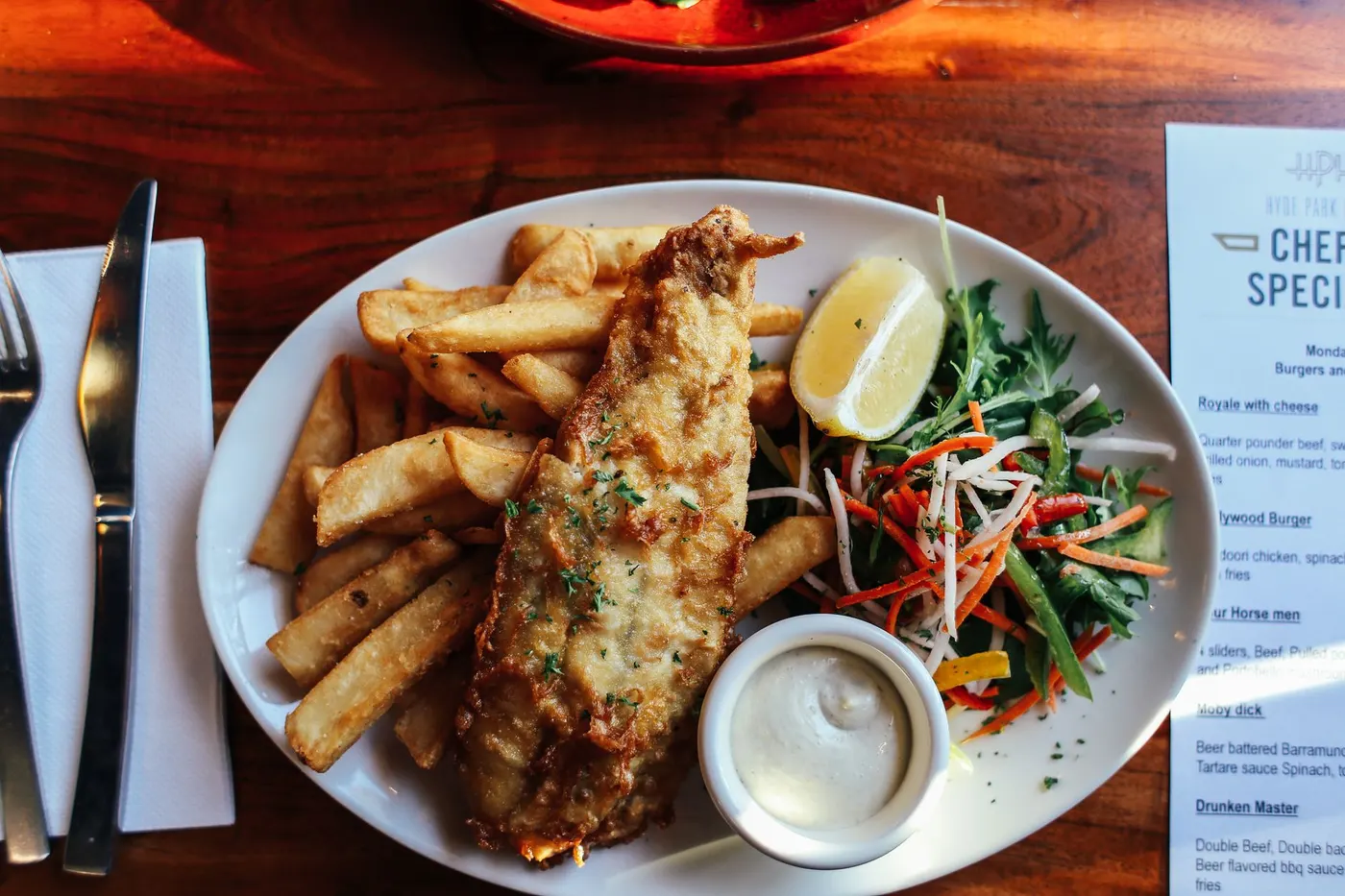 Battered fish and chips with lemon and tartare on a white plate